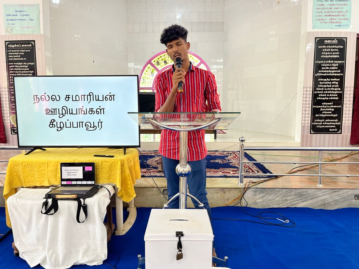 Young man preaching at the pulpit with worship screen display