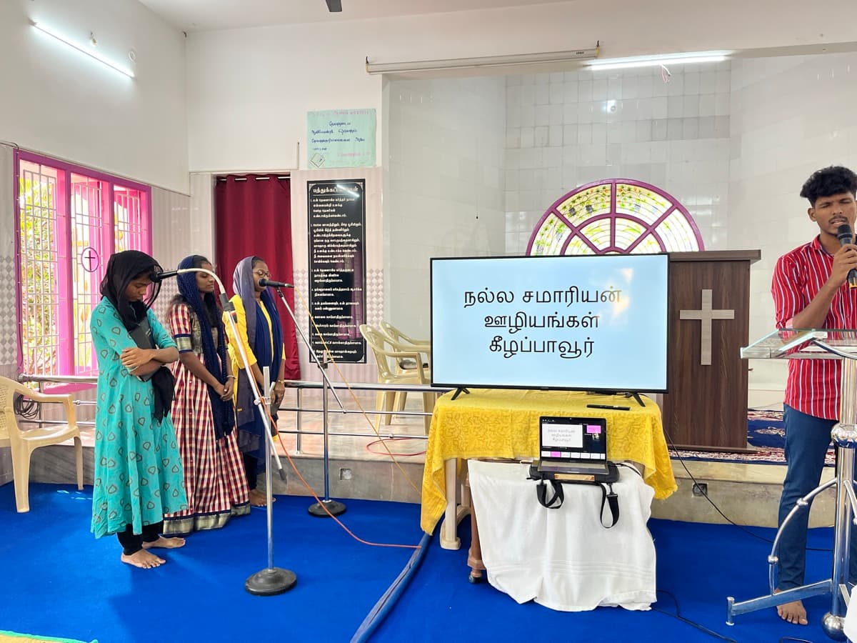 Women leading worship songs at Good Samaritan Mission with Tamil display screen